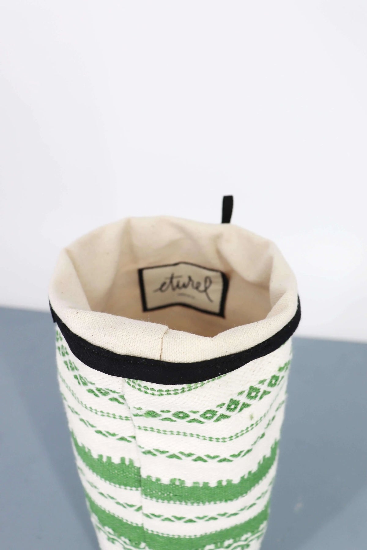 Funda para jarrón de tela con patrón geométrico alpujarra en verde y blanco, con ribete superior negro.