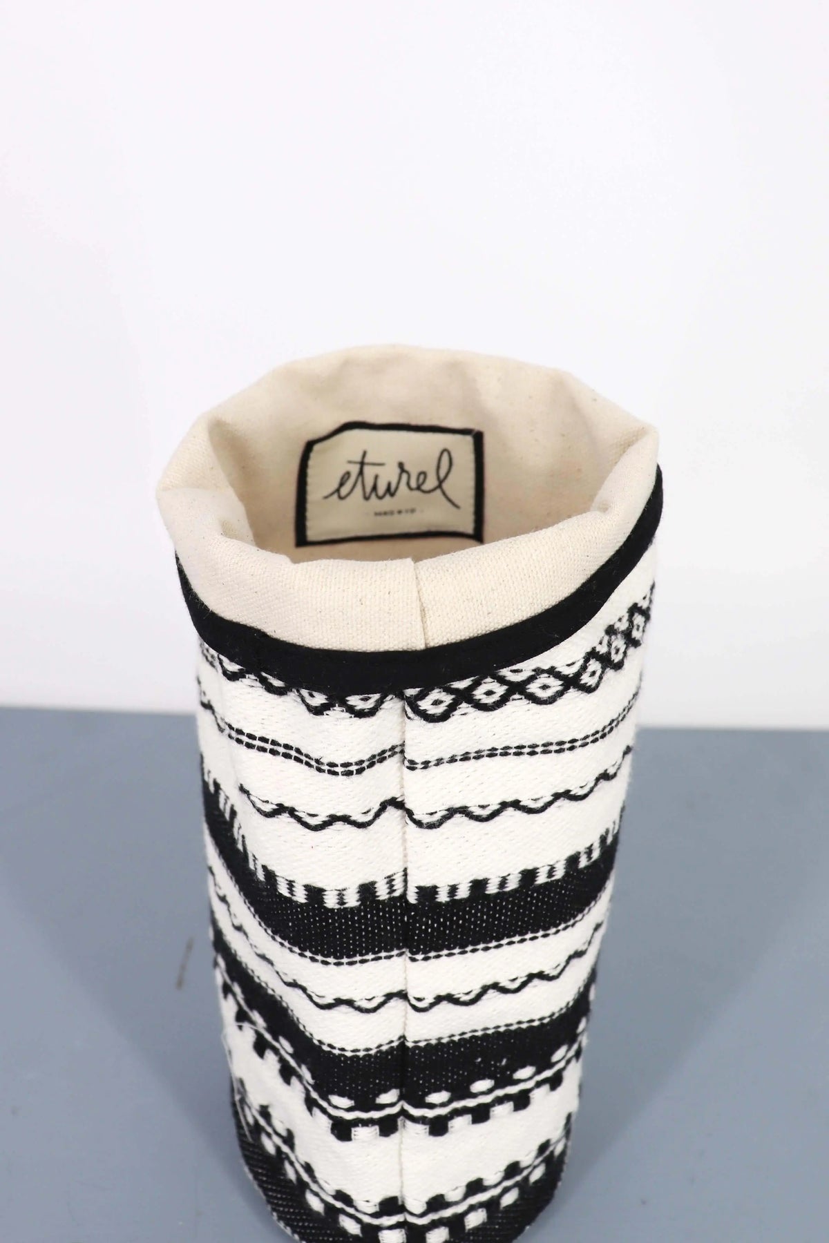 Funda para jarrón de tela con diseño geométrico artesanal en blanco y negro, estilo rústico con interior en beige.