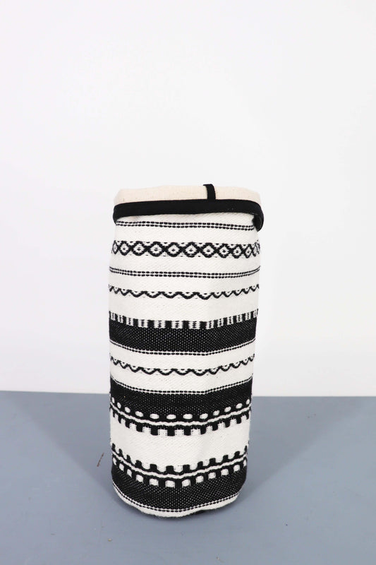 Funda cilíndrica de tela en blanco y negro con patrones geométricos y étnicos tejidos, estilo rústico decorativo.