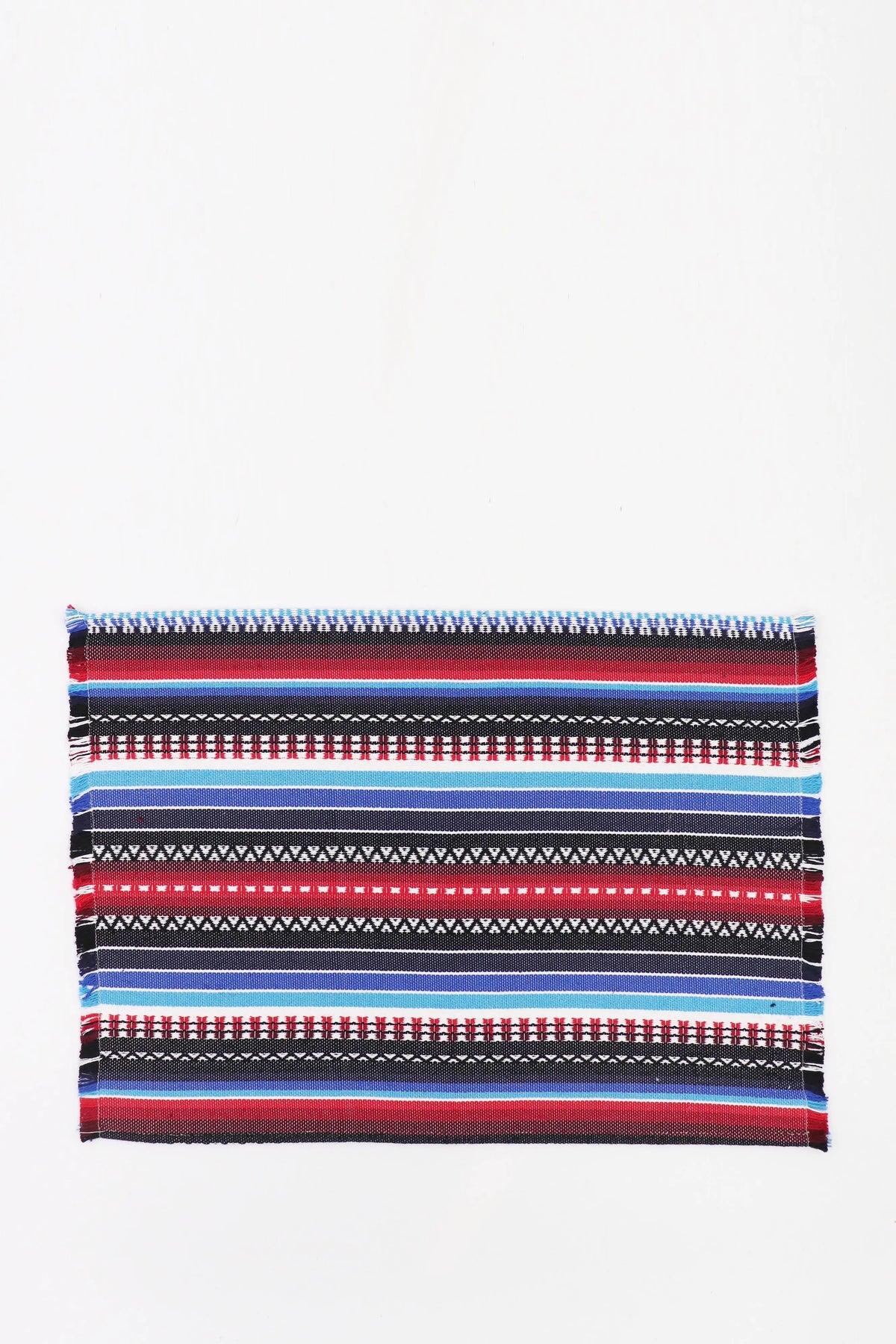Rectangular placemat with traditional Manchego-style woven stripes in blue, red, black, and white with fringed edges.
