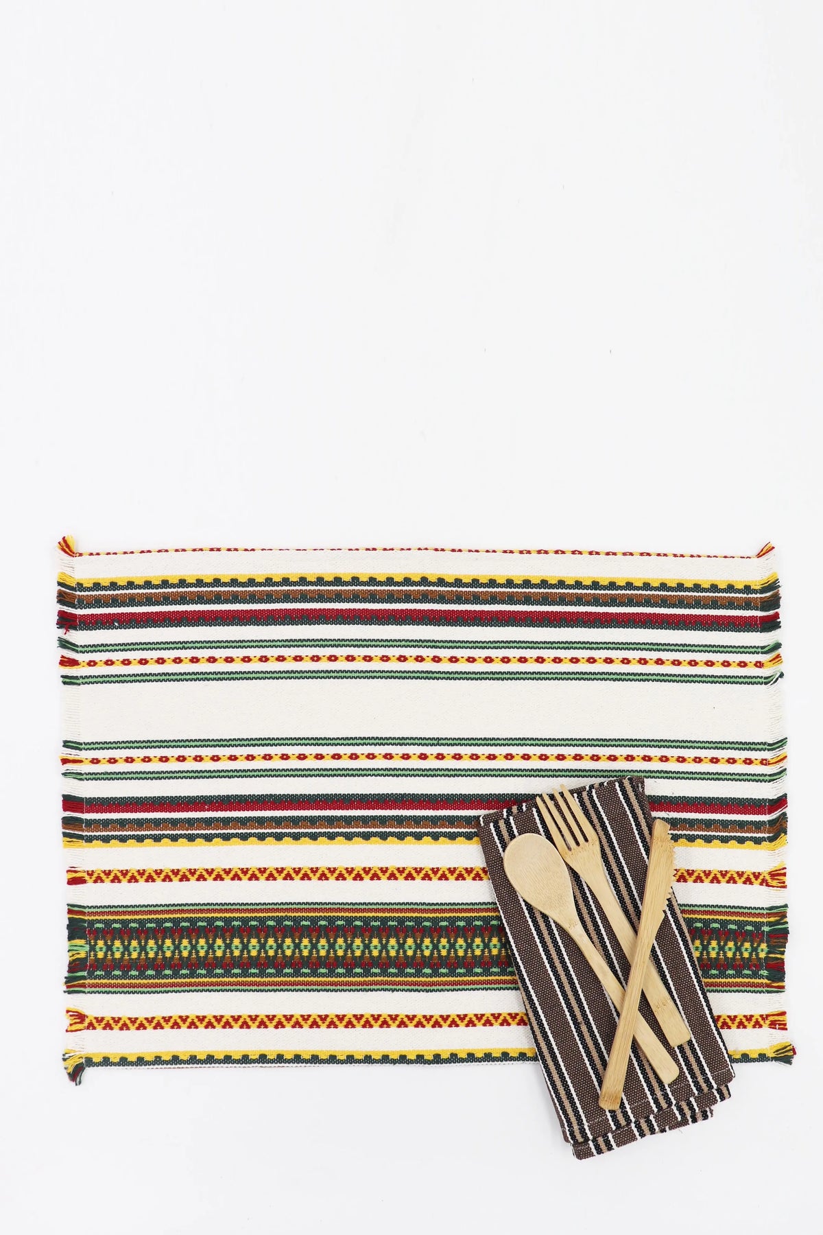 Pack de 2 manteles individuales de tejido manchego crudo con rayas multicolores y flecos, junto a cubiertos de madera.