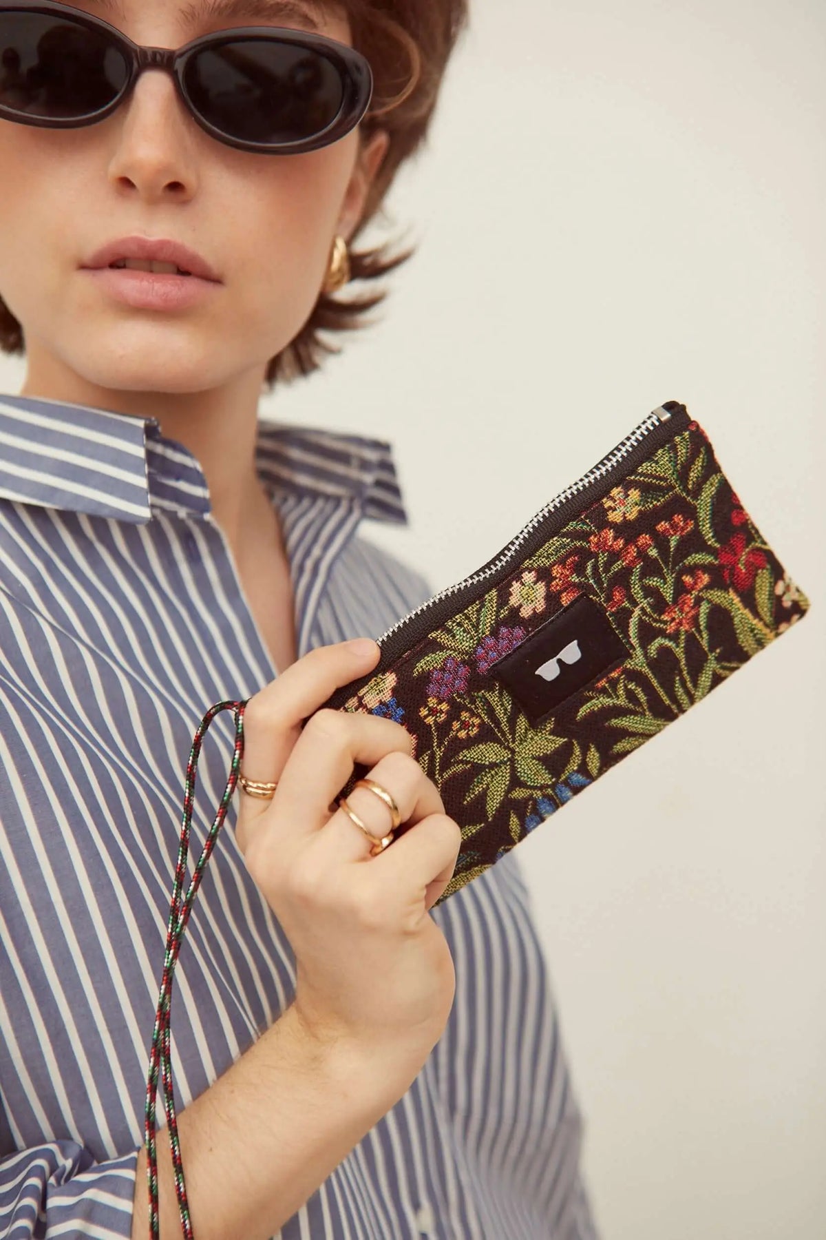 Funda de gafas de tejido jacquard con estampado de flores coloridas y margaritas sobre fondo oscuro y cierre de cremallera.