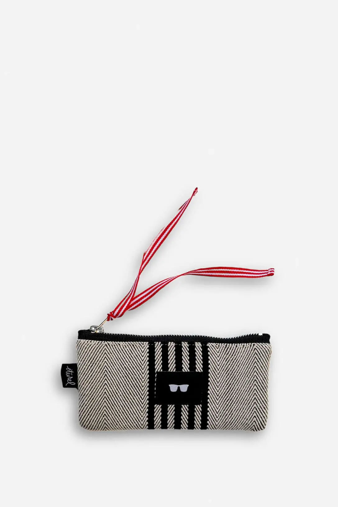 Funda de gafas rectangular en tejido de sarga beige y negro con cierre de cremallera y tirador de rayas rojas.