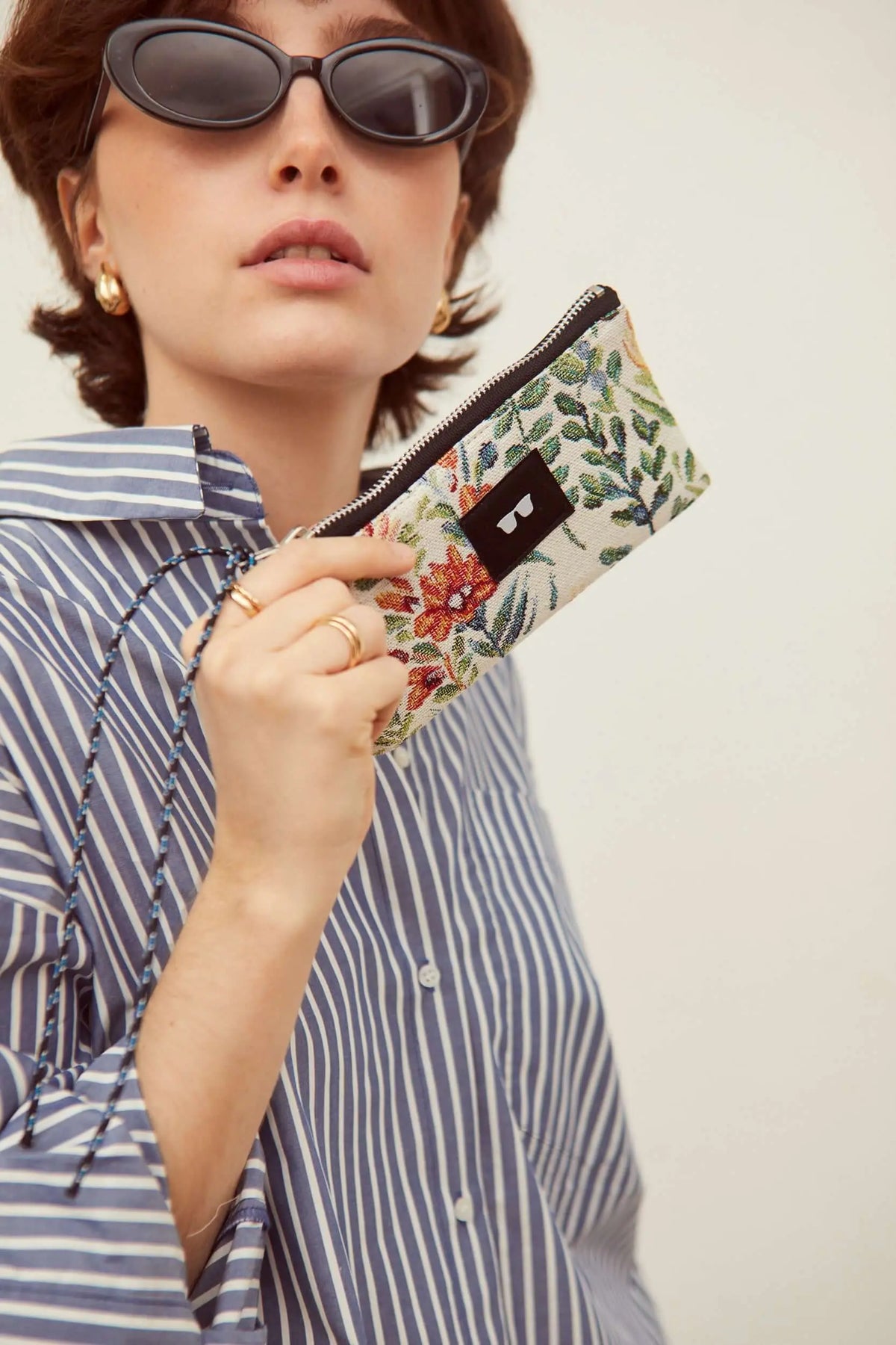 Rectangular jacquard glasses case with colorful azalea floral pattern, zip closure, and a blue cord wrist strap.