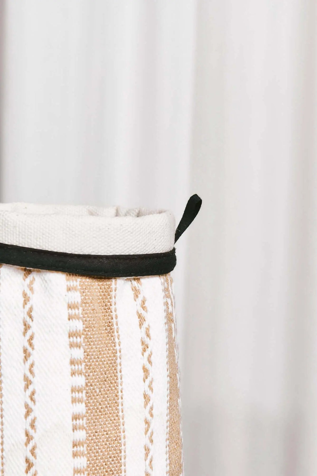 Funda de jarrón textil con rayas verticales en tonos crudo y beige, detalle de borde negro y estilo artesanal.