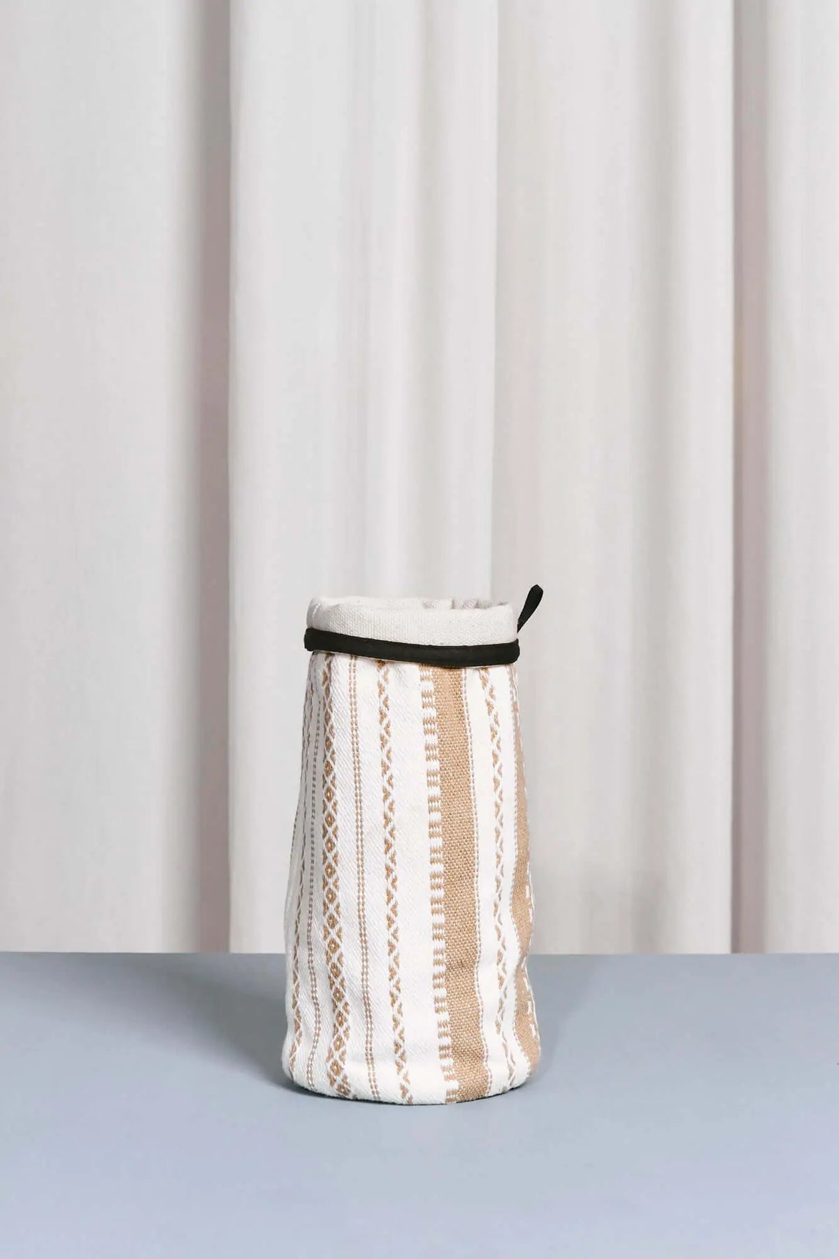 Cylindrical vase cover in cream and beige striped cotton fabric with textured geometric patterns and a black rim.