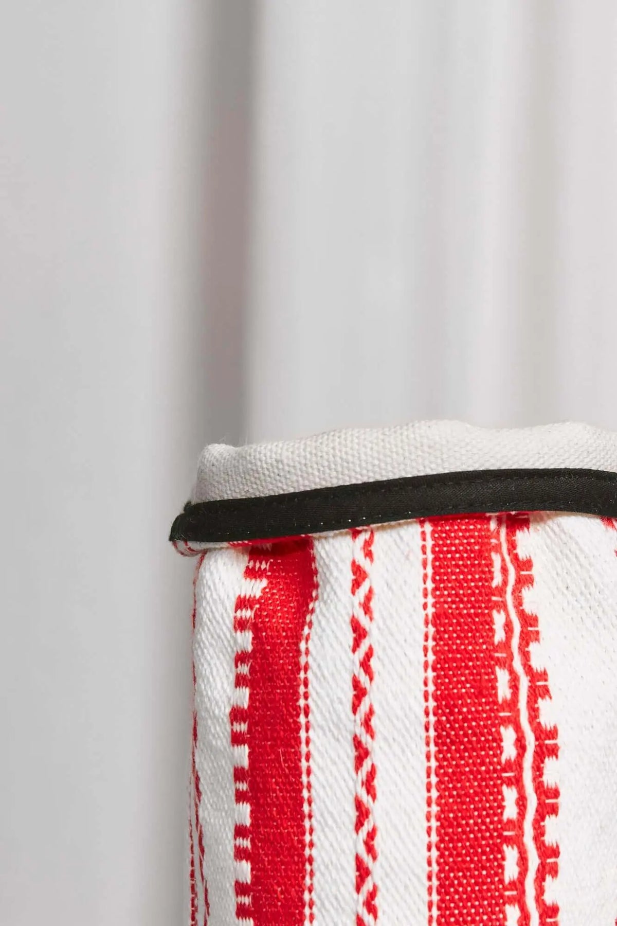 Funda textil de jarrón con estampado de rayas verticales rojas sobre fondo blanco y borde superior en color negro.