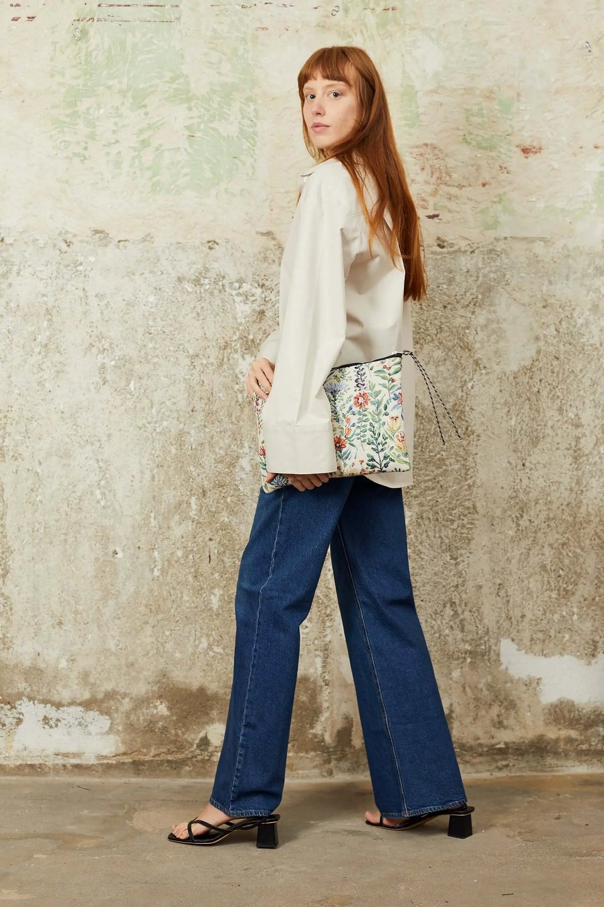 Mujer sostiene funda para ordenador o iPad de tejido jacquard con estampado floral de azaleas en tonos vivos.