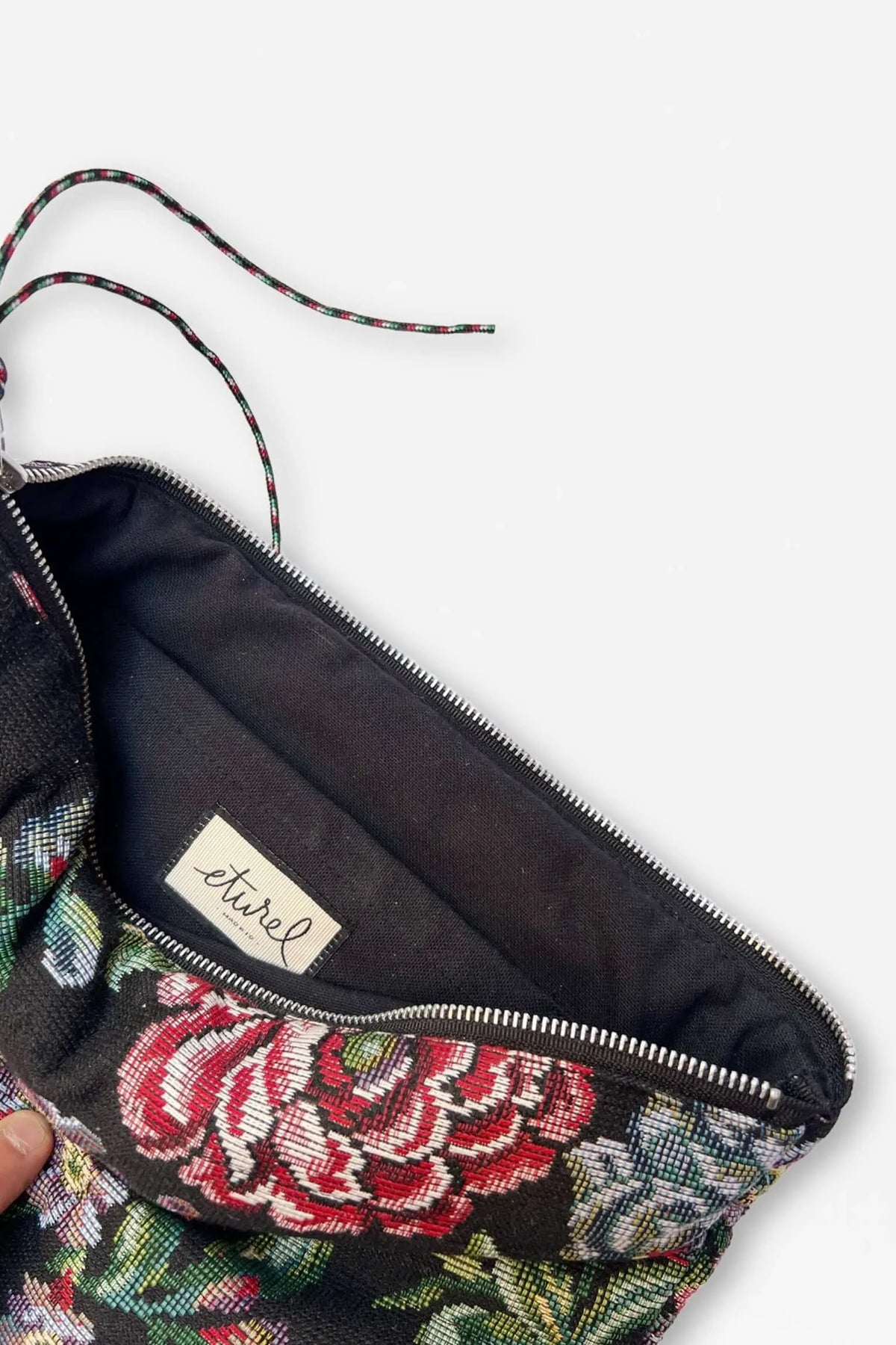 Funda de ordenador de tela jacquard negra con estampado floral de peonías, cierre de cremallera e interior forrado.