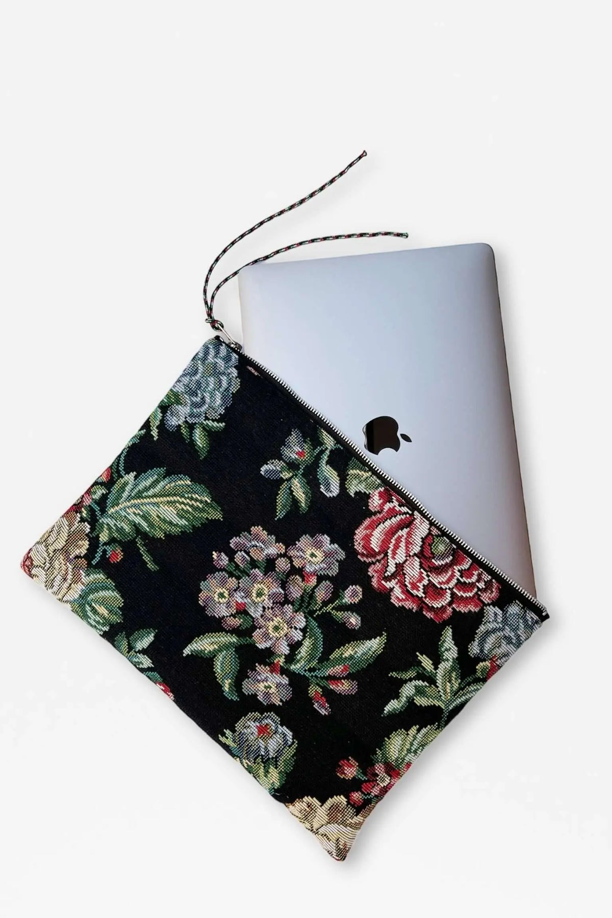 Laptop sleeve in black floral jacquard fabric featuring colorful peonies, with a zipper closure and pull cord.