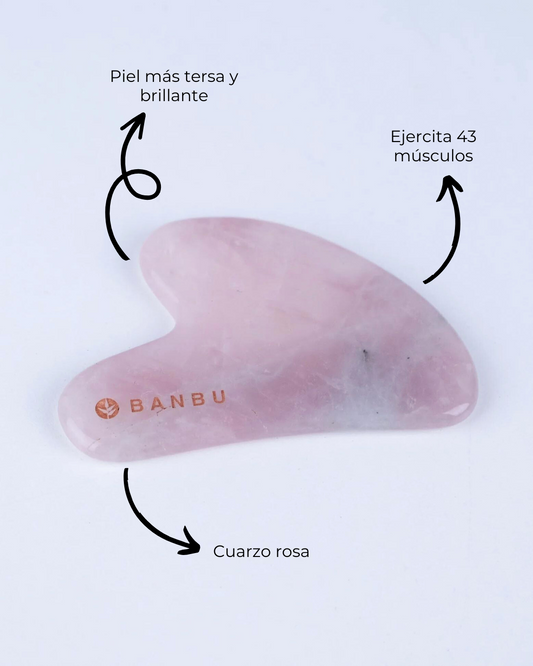 Gua Sha de cuarzo rosa suave y brillante de marca Banbu, con flechas explicativas sobre sus beneficios y material.