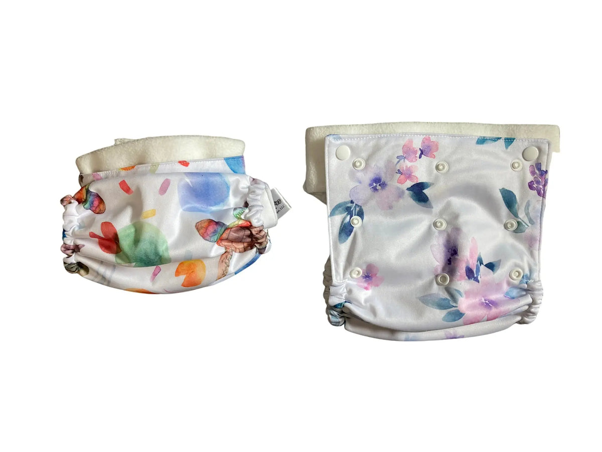 Printed PUL diaper cover with belt, featuring colorful abstract and floral designs, elasticized edges, and snap buttons.