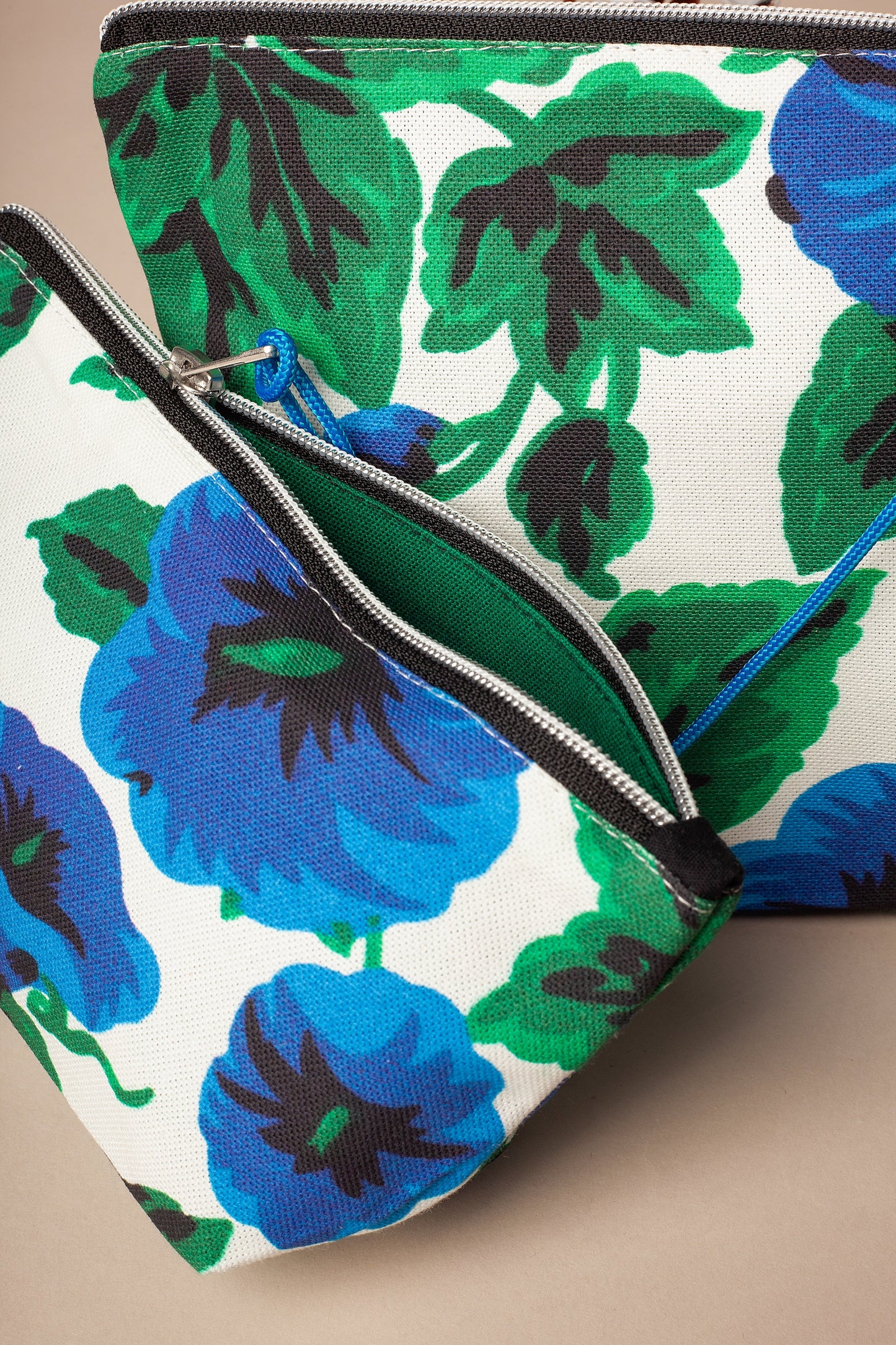 Two zippered canvas toiletry bags featuring a bold blue and green floral print on a white background.