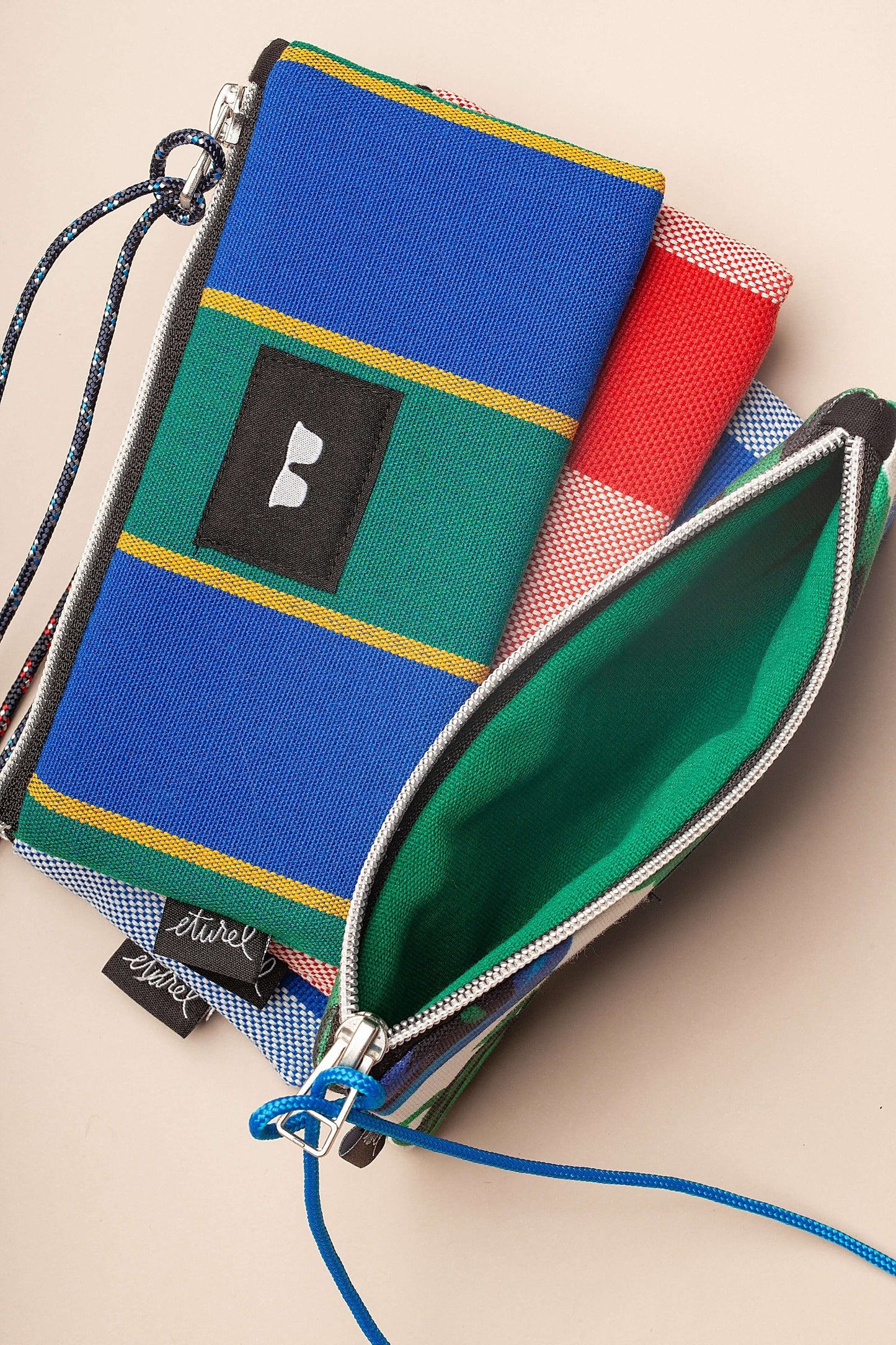 Striped canvas glasses cases in blue, green, and red with zipper closures and matching carry cords.