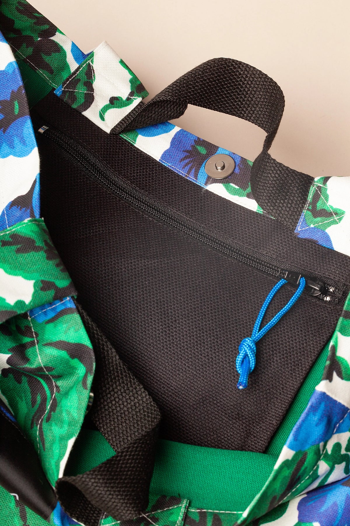 Bolso tote de lona con estampado floral, interior negro con cierre de cremallera y asas resistentes.