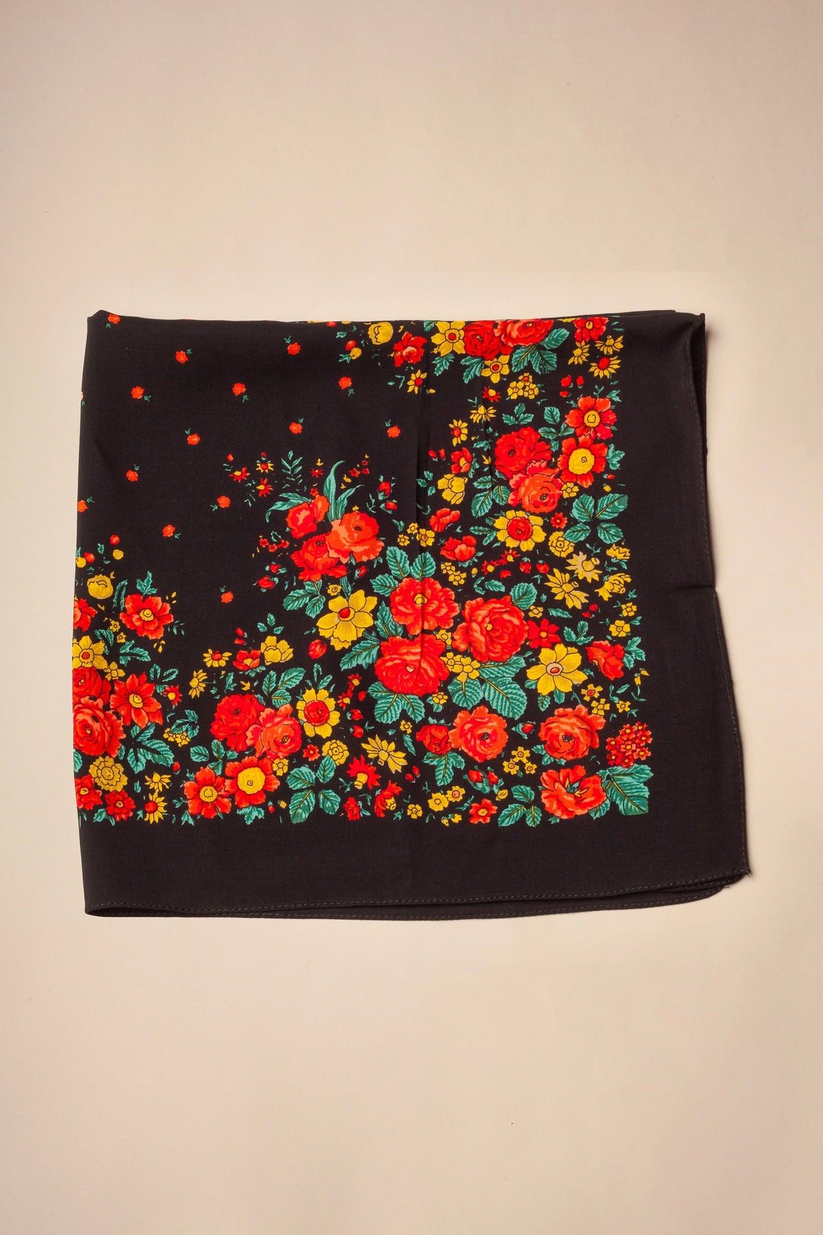 Black square scarf with vibrant red and yellow floral print and green leaves in a traditional folk style.