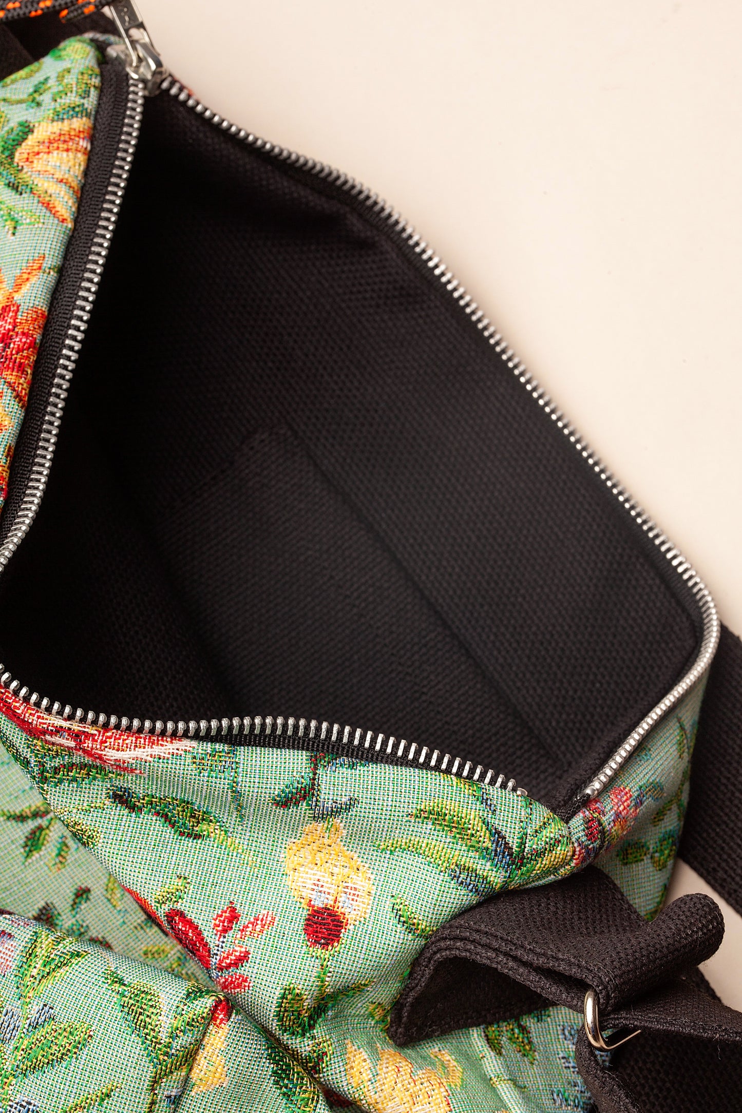 Bolso bandolera de tejido jacquard con estampado floral en tonos celestes, amarillos y rojos, con interior negro.