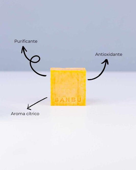 Jabón sólido Banbu amarillo sobre fondo blanco. Señala sus beneficios: purificante, antioxidante y aroma cítrico.