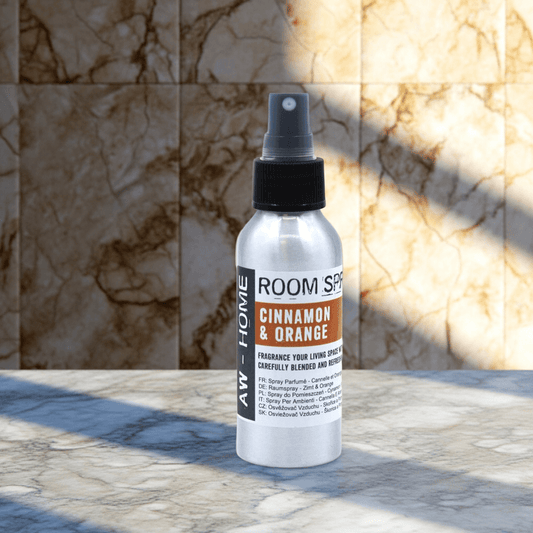Ambientador en spray de 100ml, botella de aluminio plateado con etiqueta de canela y naranja sobre fondo de mármol.