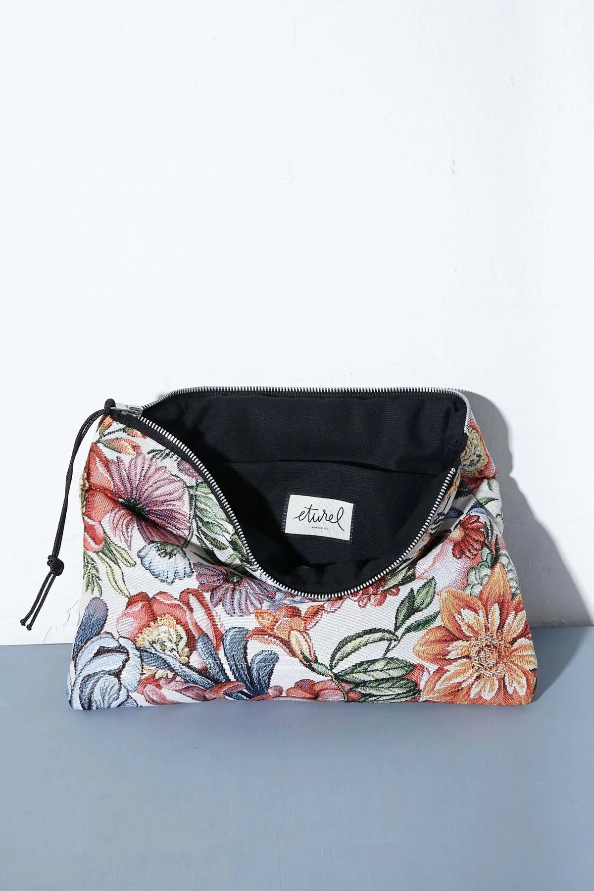 Funda para ordenador con tejido jacquard de flores estilo crisantemos en tonos rojos y naranjas sobre fondo claro.