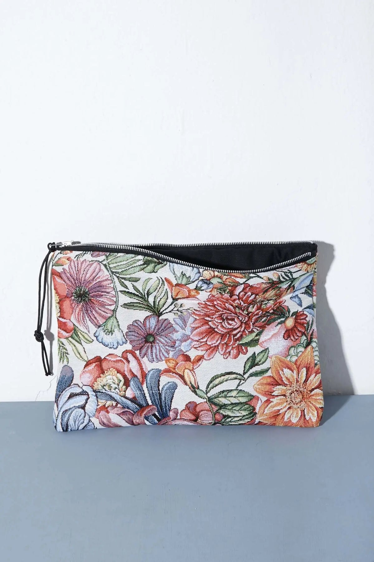 Funda rectangular de tejido jacquard con estampado de flores y crisantemos rojos, cremallera negra y cierre lateral.