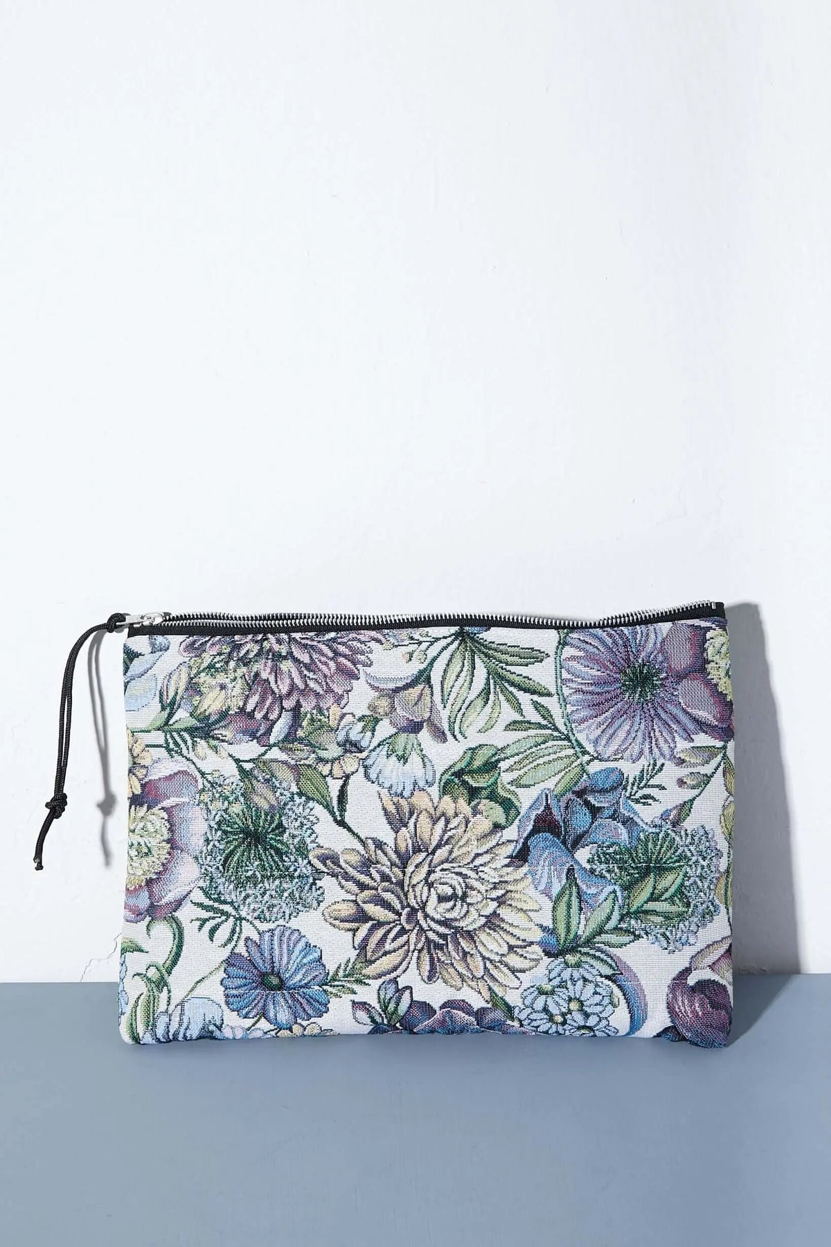 Funda rectangular de tela jacquard con estampado de crisantemos en tonos azules, morados y verdes y cierre de cremallera.