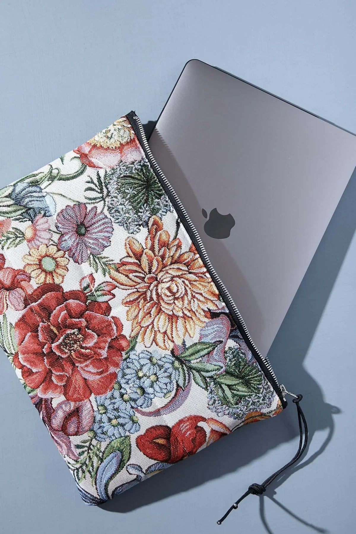Funda de ordenador en tejido jacquard con estampado de flores y crisantemos rojos, con cierre de cremallera negro.