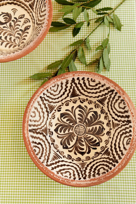 Lebrillos de cerámica artesanal con motivos florales negros sobre fondo crema y borde de barro natural visto.