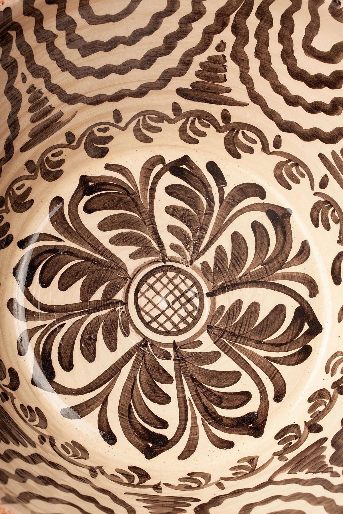 Lebrillo de cerámica con fondo crema y motivos florales y geométricos pintados en color negro.