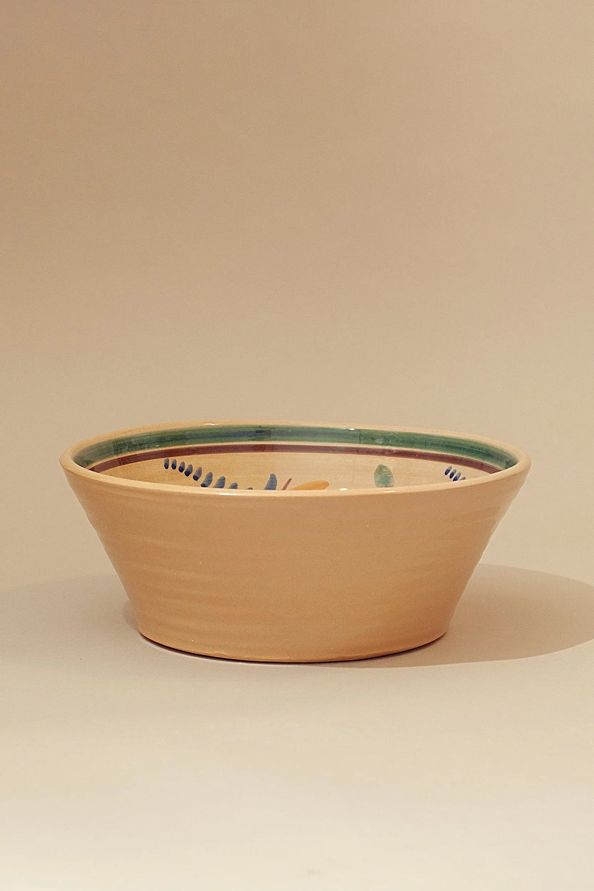 Cuenco de cerámica color terracota con borde verde, decorado en estilo floral, ideal para servir y decorar.