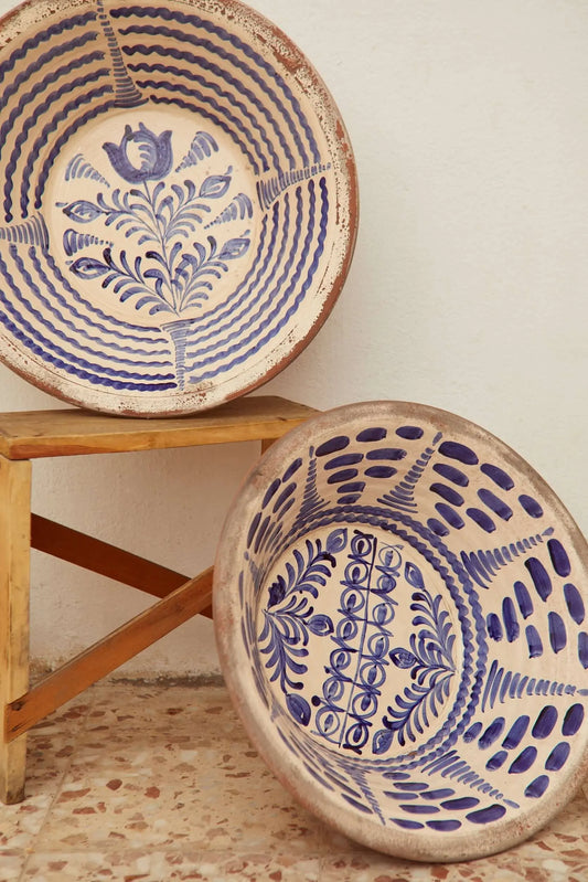 Dos lebrillos de cerámica granadina con decoración floral en azul sobre fondo crema, apoyados en un taburete de madera.