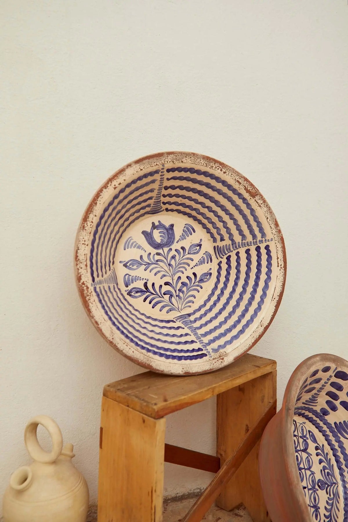 Lebrillo de cerámica artesanal con patrón de espirales y motivos florales en azul sobre fondo crema. Estilo tradicional.