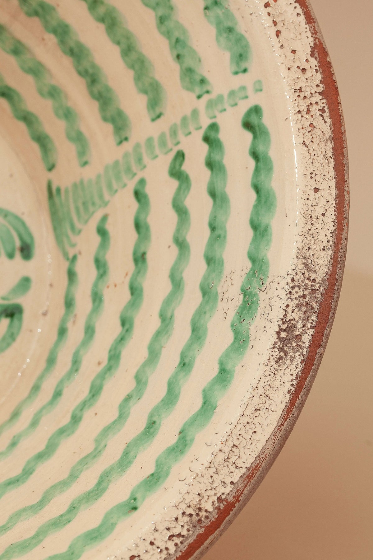 Lebrillo de cerámica artesanal con esmalte crema, decorado con líneas onduladas en color verde y acabado rústico.