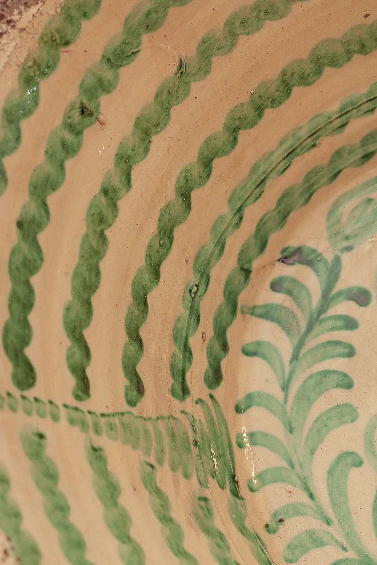 Lebrillo de cerámica artesanal con motivos vegetales en color verde sobre fondo crema, estilo tradicional granadino.