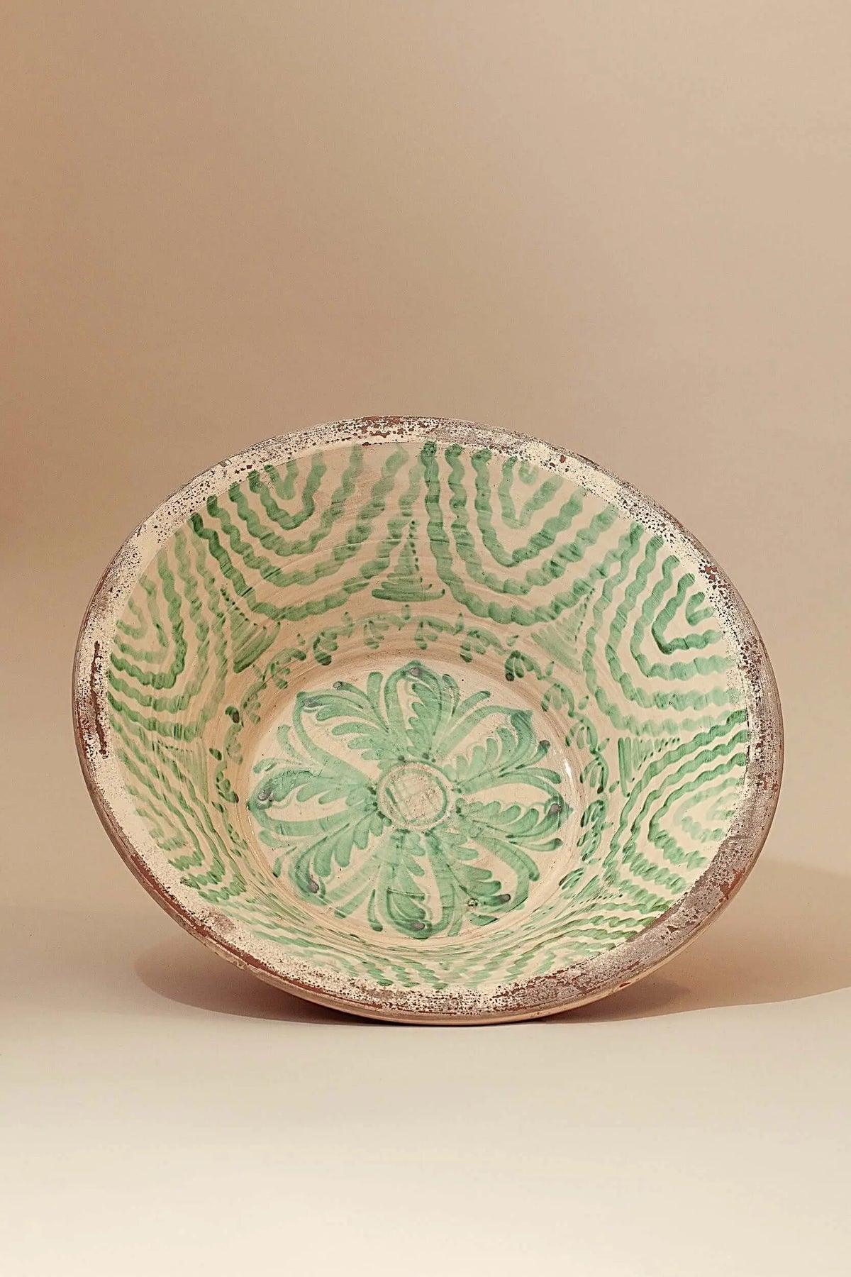 Lebrillo de cerámica artesanal con motivos florales y geométricos pintados en color verde sobre fondo crema.