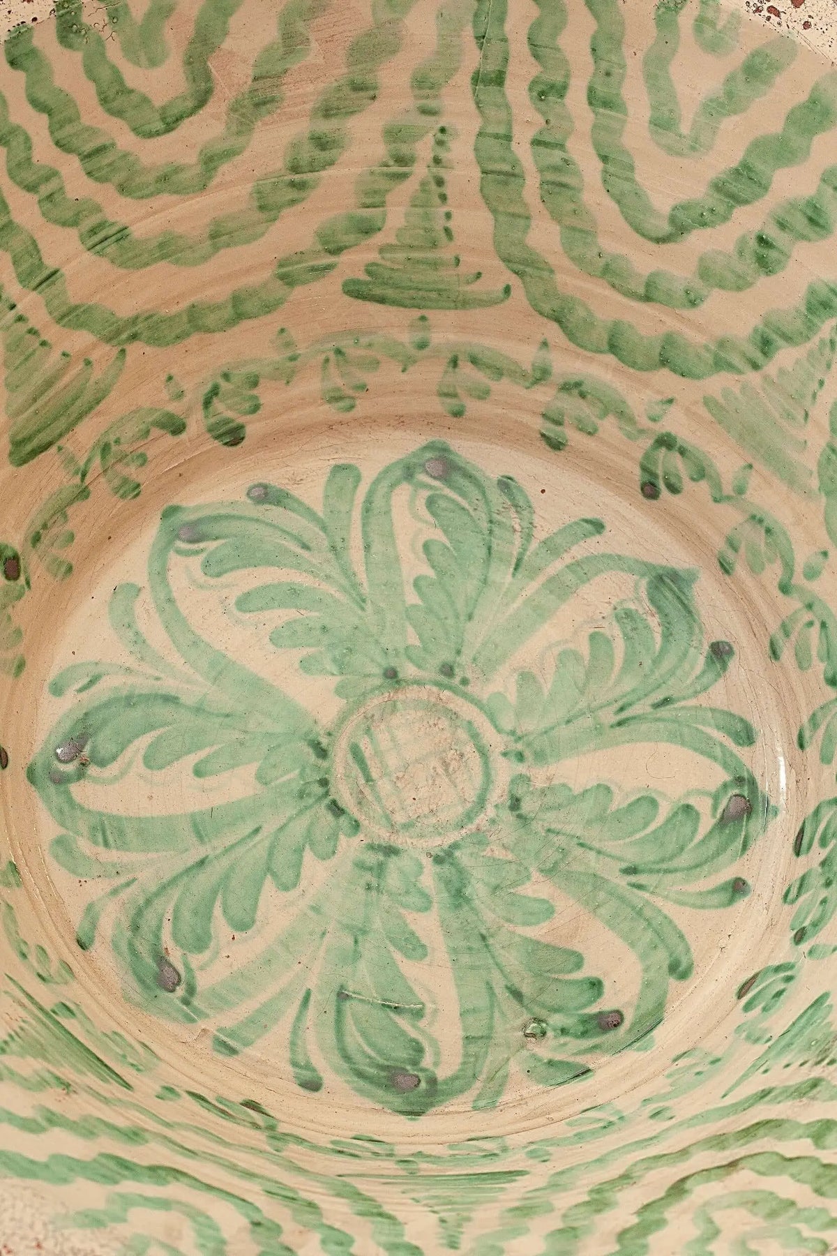 Lebrillo de cerámica artesanal con motivos florales y geométricos pintados en color verde sobre fondo crema.