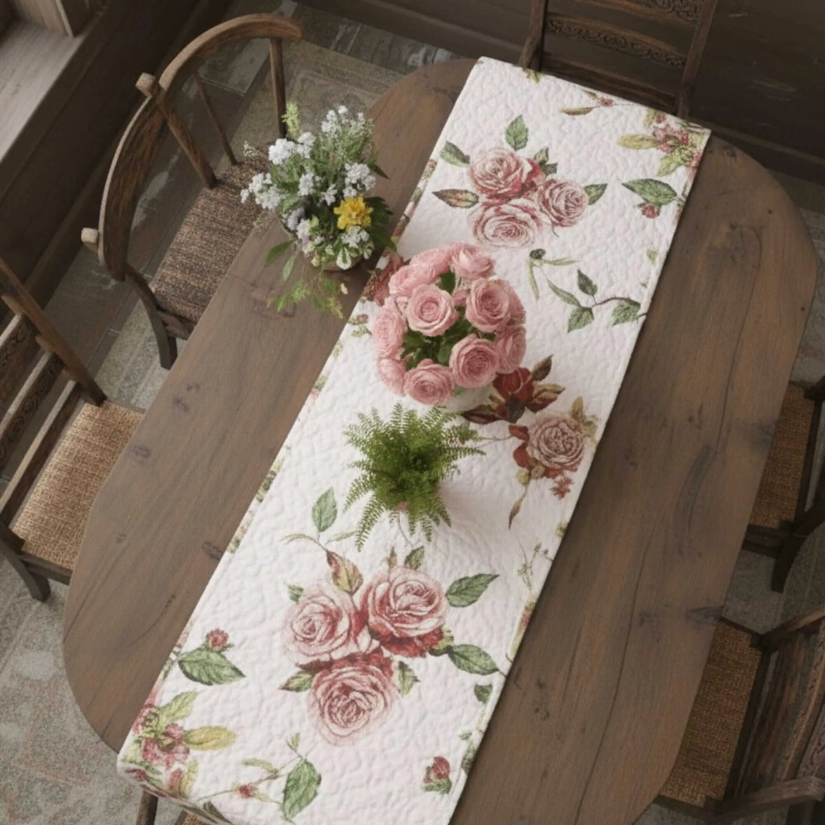 Quilted white dining table runner featuring a romantic pink and green rose floral print on a wooden dining table.