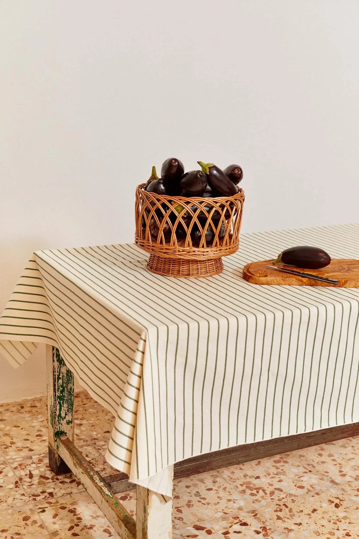 Mantel de lino en color crema con finas rayas verticales verdes sobre una mesa rústica, estilo decorativo natural.