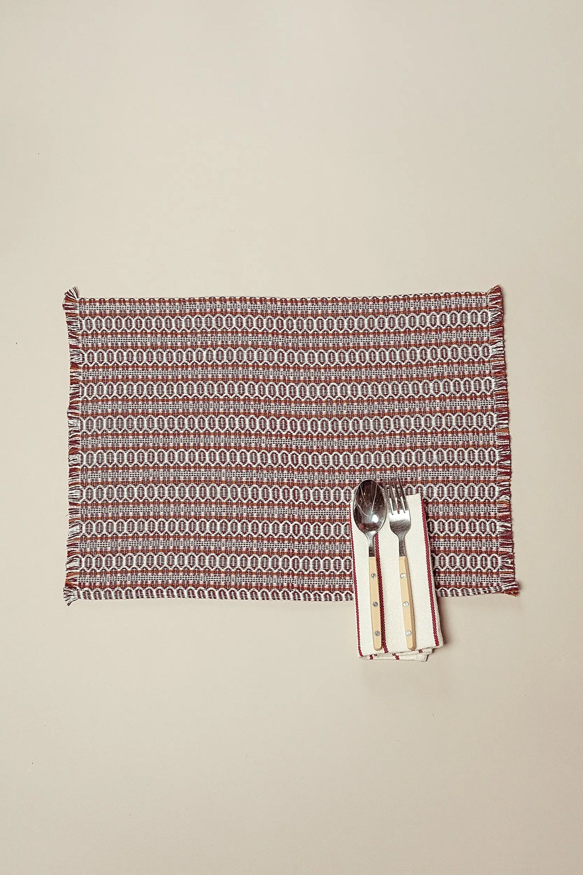 Pack de 2 manteles individuales de tela granate con estampado ojo de perdiz retro, bordes desflecados y cubiertos.