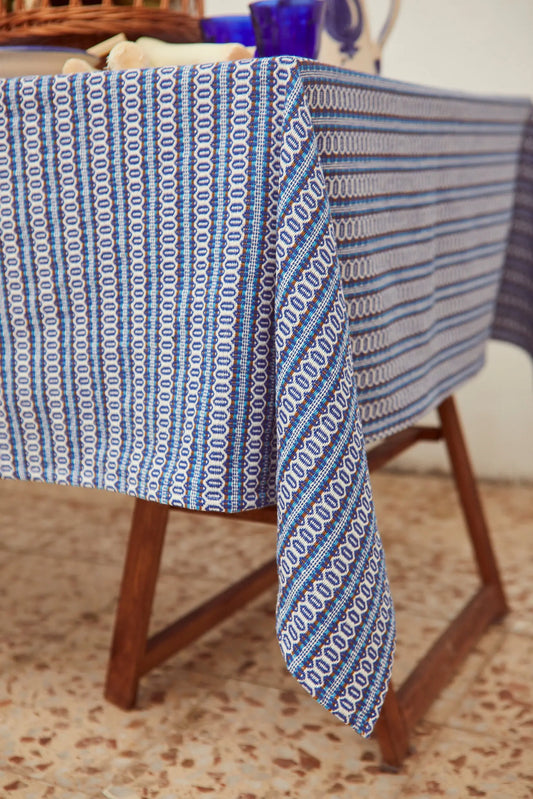 Mantel textil con patrón de rayas verticales y tejido de ojo de perdiz en tonos azul, blanco y marrón estilo retro.