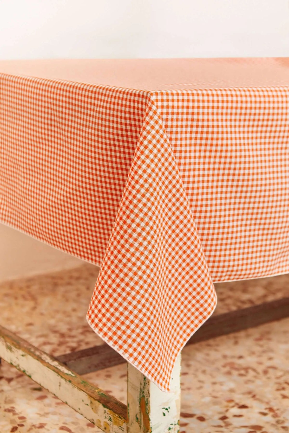 Tablecloth with an orange and white checkered gingham pattern, draped over a wooden table.