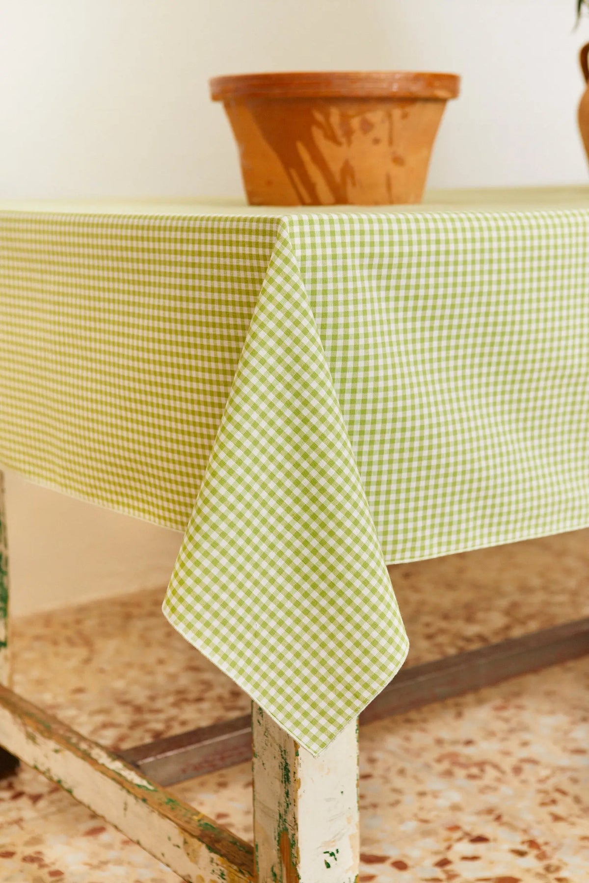 Mantel de tela con estampado de cuadros vichy en color verde y blanco sobre una mesa rústica.