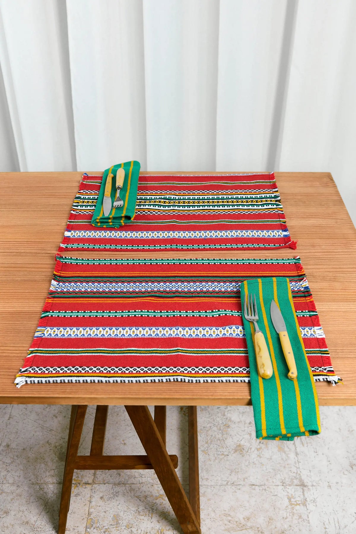 Mantel de mesa colorido rojo, verde y amarillo, tejido artesanal, con cubiertos y servilletas a juego.