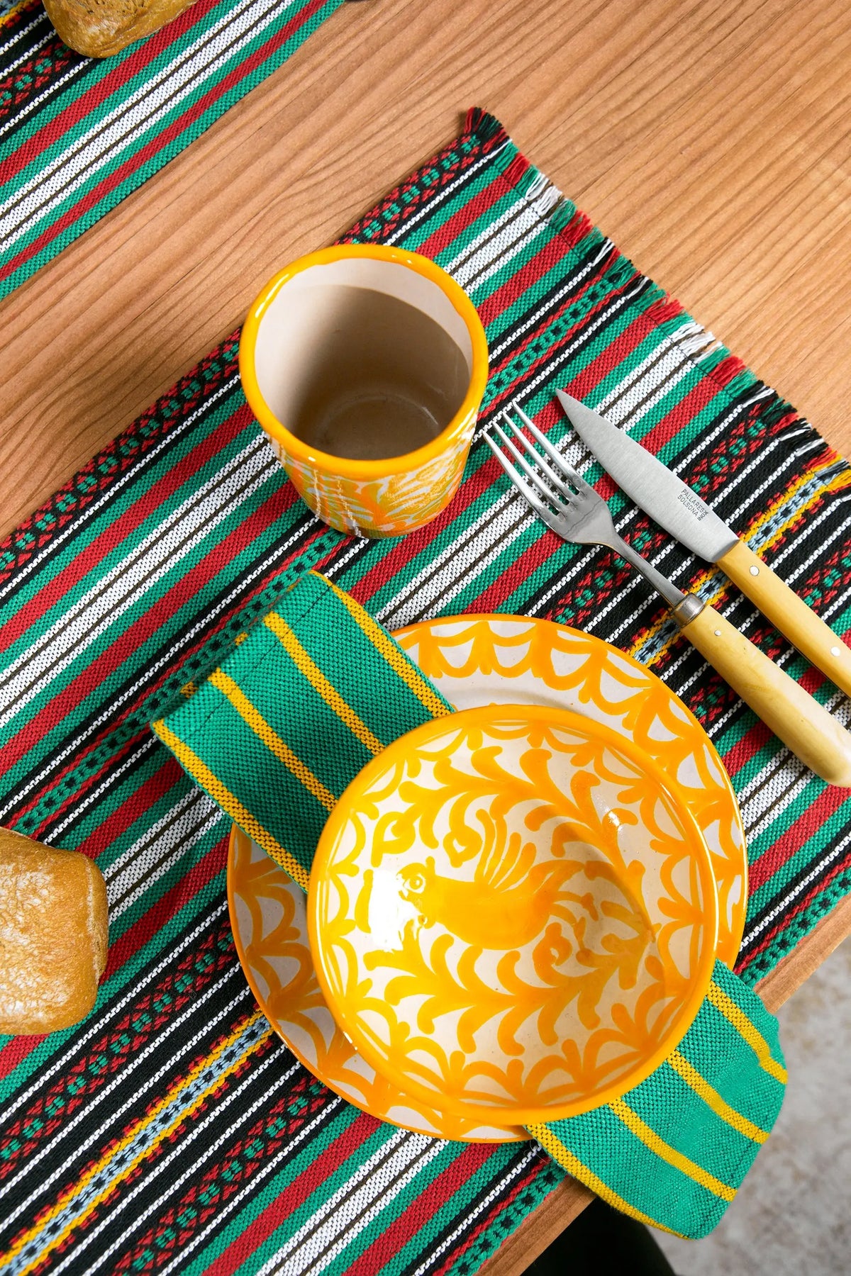 Dos servilletas de tela con rayas verticales verdes y amarillas, dispuestas sobre una mesa de madera.