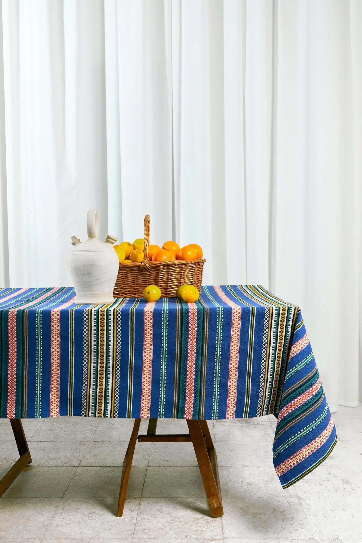 Blue tablecloth featuring colorful woven vertical stripes with decorative geometric patterns on a wooden table.