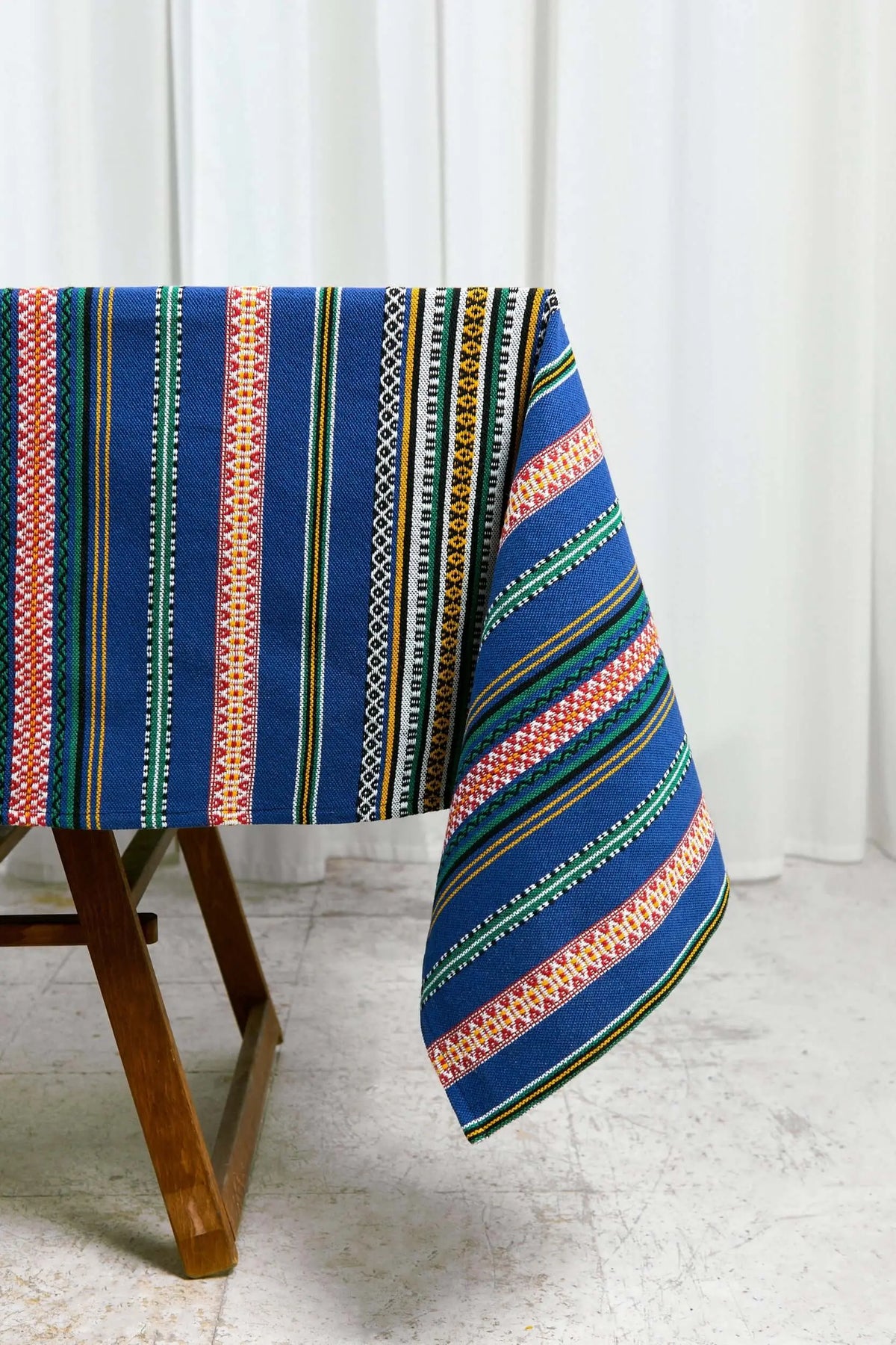 Mantel azul con estampado de rayas verticales multicolores y patrones geométricos, estilo artesanal y tejido resistente.