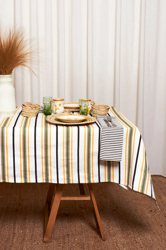Mantel tejido estilo canario con rayas verticales en verde, amarillo y negro sobre fondo blanco.