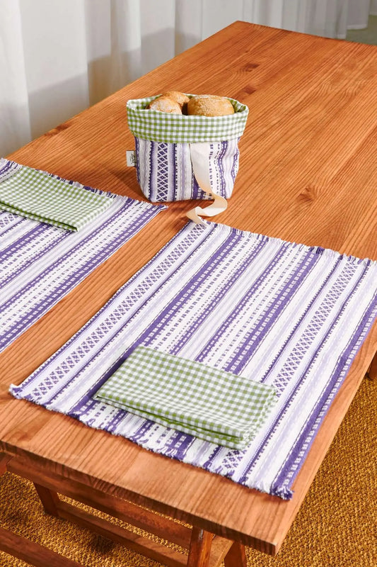 Two rectangular mauve and white striped placemats with fringed edges, paired with folded green gingham napkins.