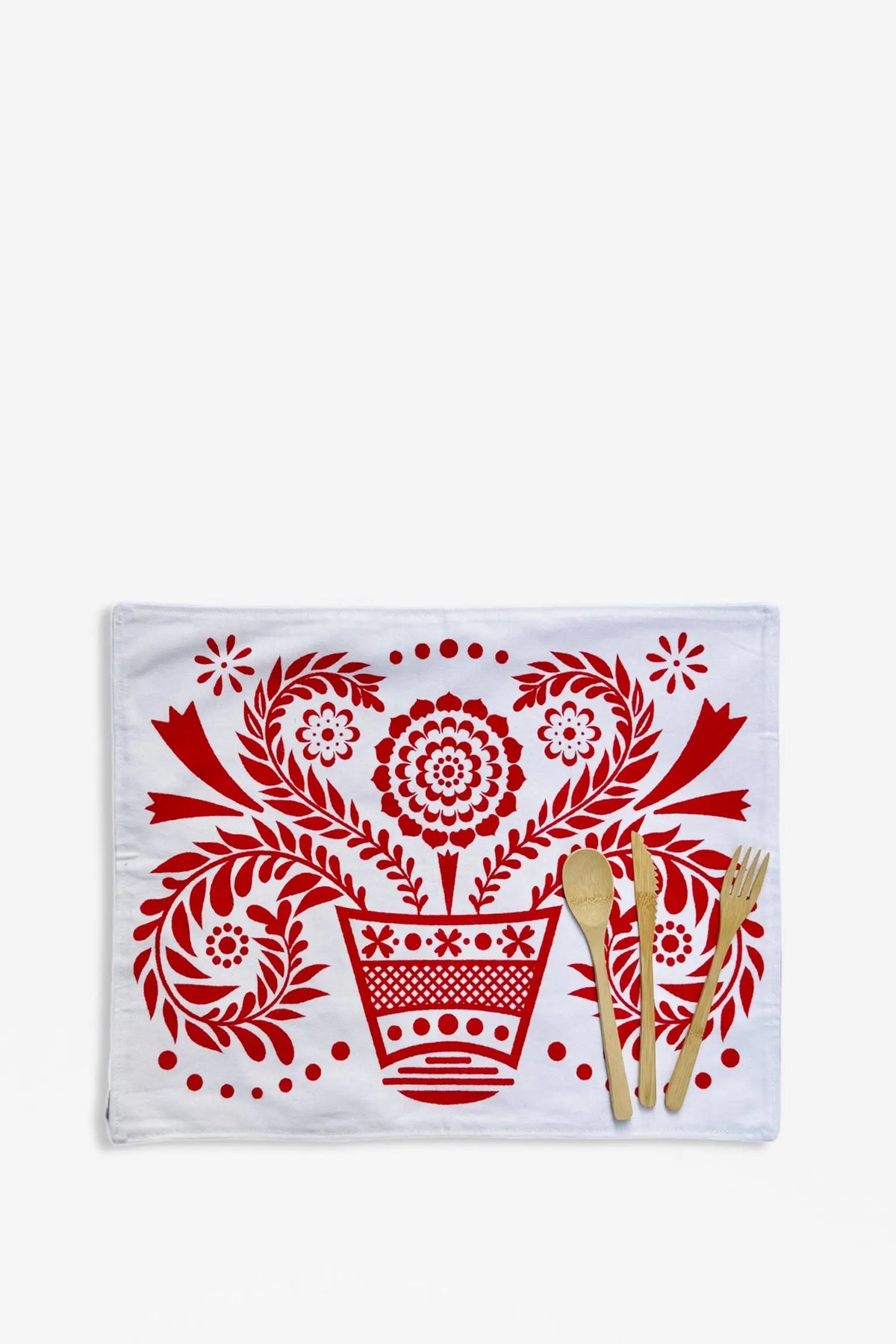 Rectangular white placemat with a red folklore floral print and matching bamboo cutlery set.