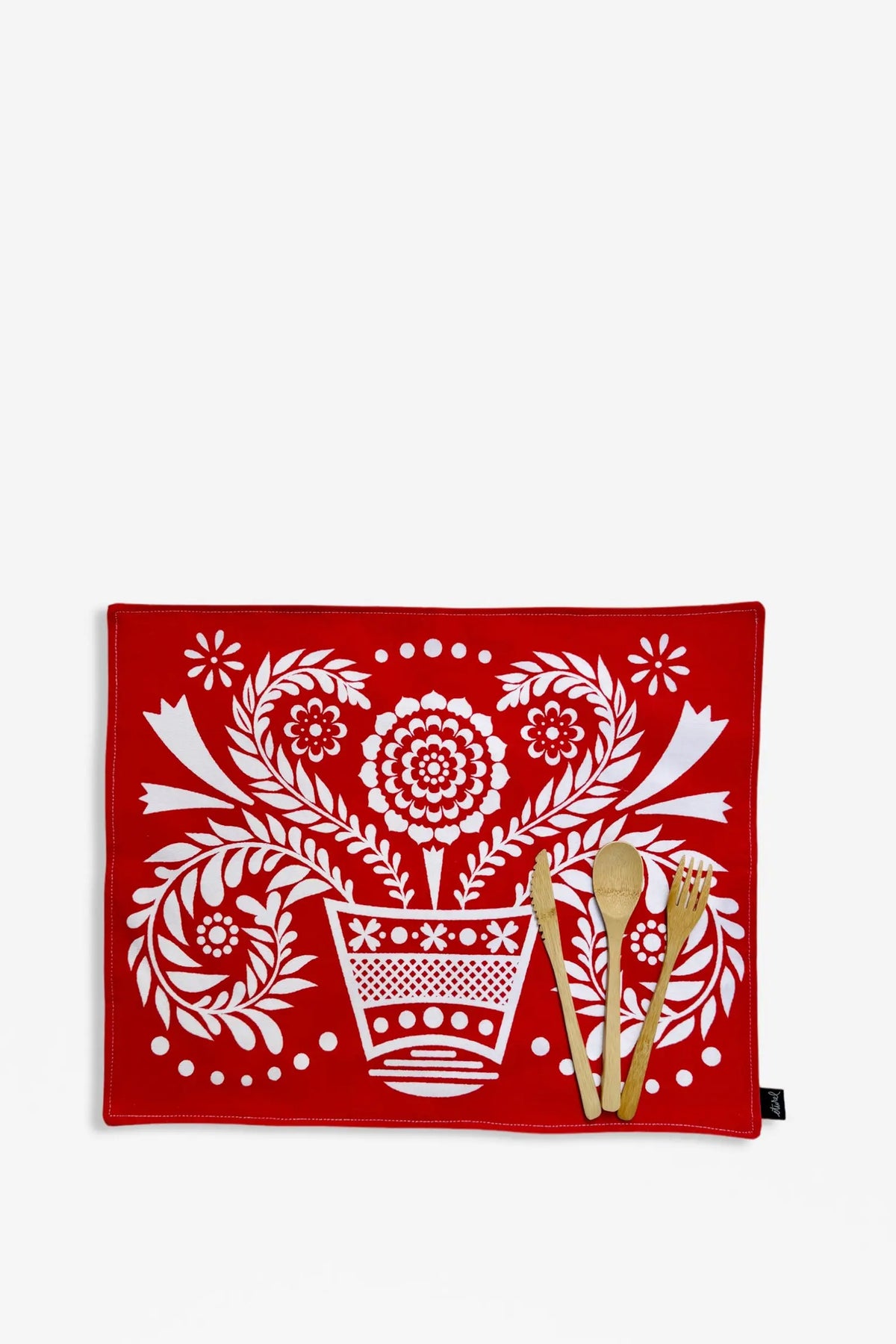 Pack de 2 manteles individuales rojos con estampado floral tipo folklore en blanco y cubiertos de madera sobre fondo.